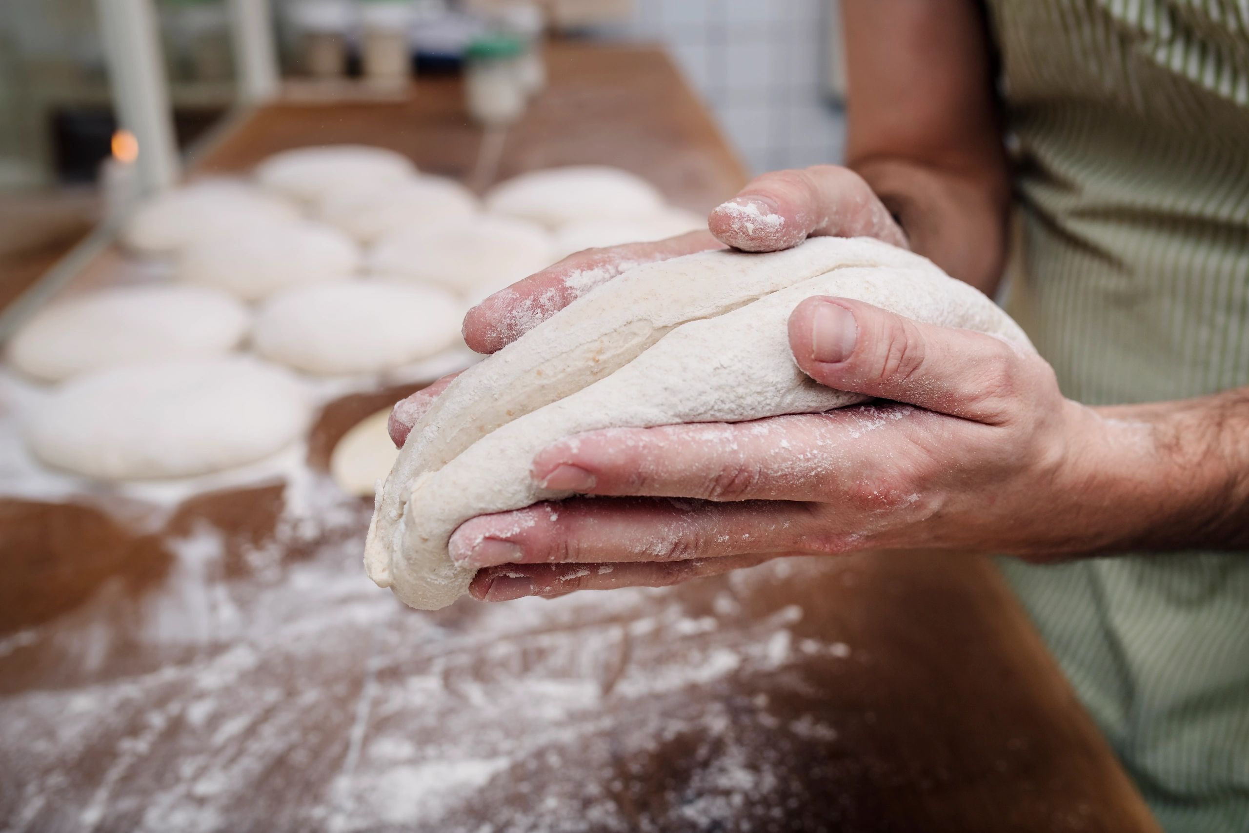 Hands shaping sourdough dough on a work surface