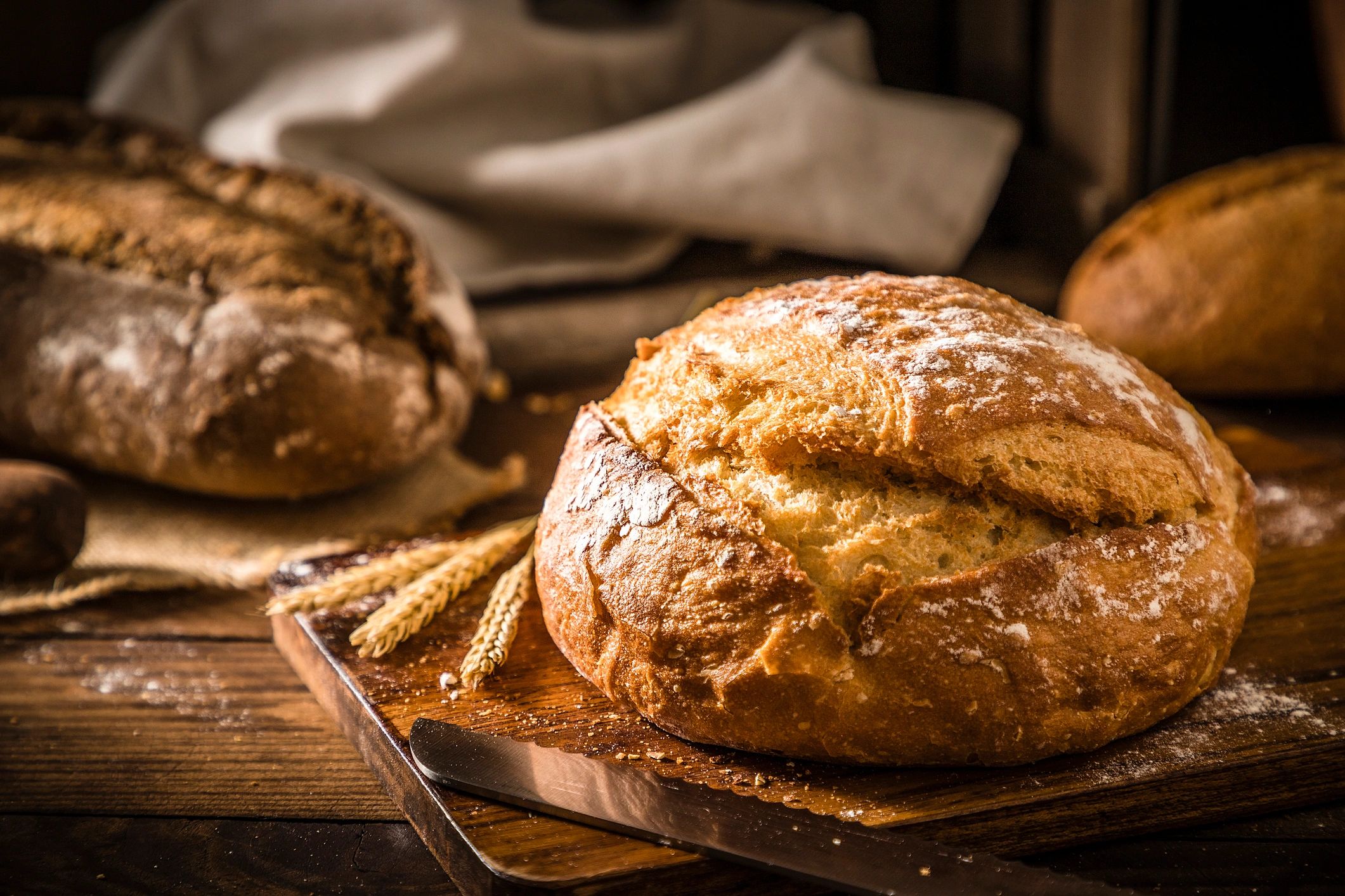 Loaf of bread on a rustic wooden table with a bread knife