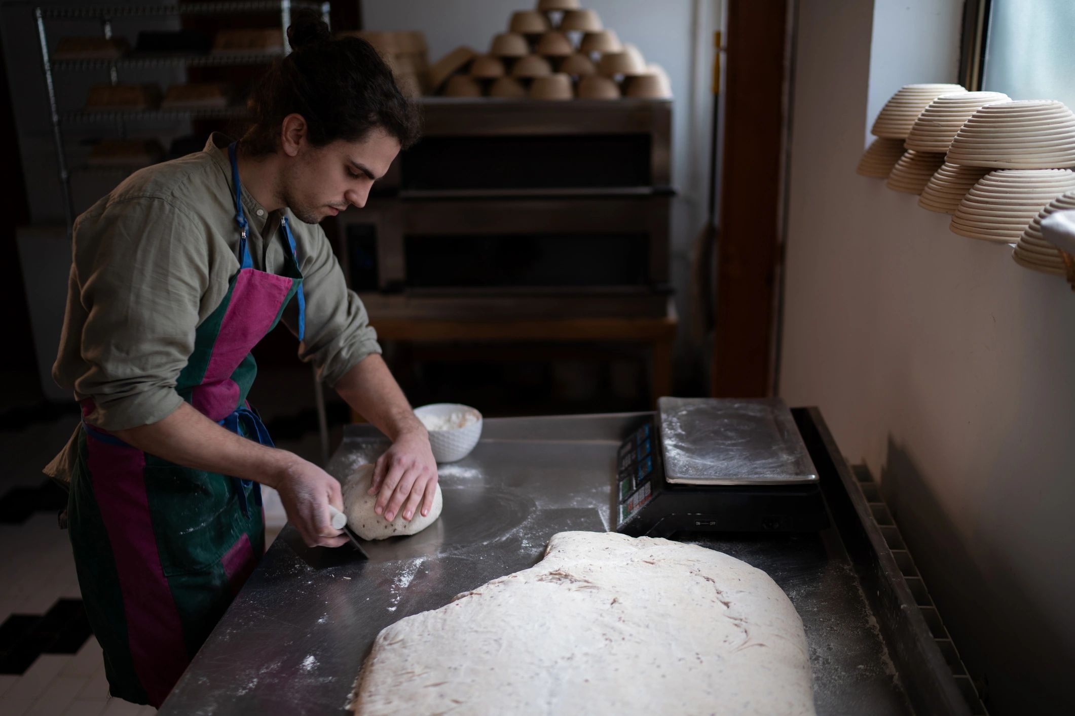 Baker dividing dough on a stainless steel worktable